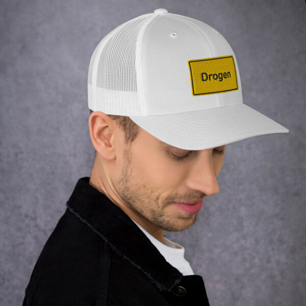 Ein Mann, der eine weiße Drogen-Trucker-Cap trägt, auf der das Wort „Drache“ zu sehen ist.