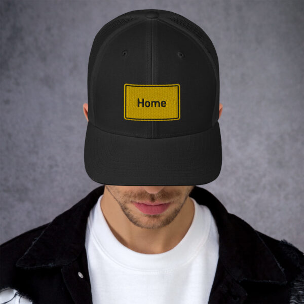 Ein Mann trägt eine Trucker-Cap mit der Aufschrift „Home“ darauf.