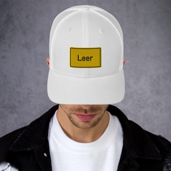 Ein Mann trägt eine weiße Trucker-Cap mit der Aufschrift „Leer“.