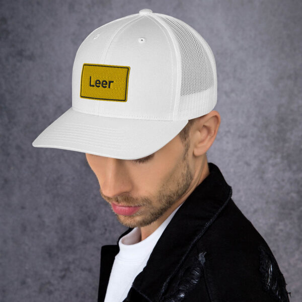 Ein Mann trägt eine weiße Trucker-Cap mit der Aufschrift „Leer“.